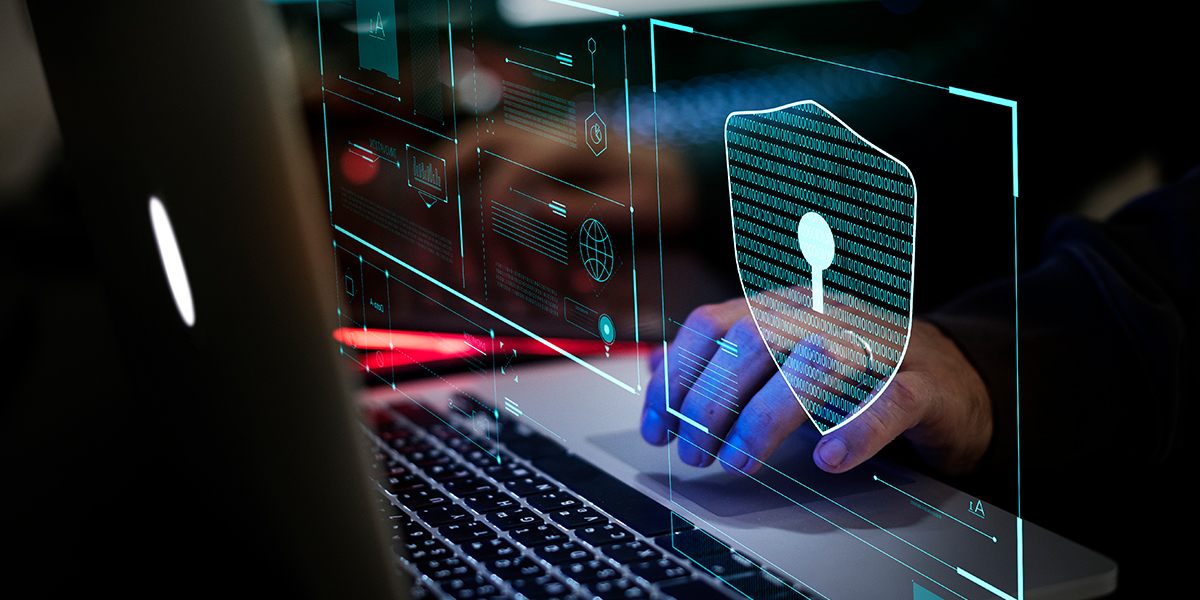 Pessoa mexendo em um computador com um cadeado na frente. A imagem remete à proteção de dados online, tema da Newsletter escrita por colaboradores do Kasznar Leonardos.