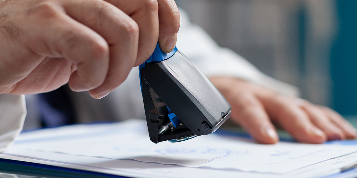 Imagem de documento sendo carimbado representando as licenças sanitárias necessárias para a produção e empreendimento no setor de cosméticos.